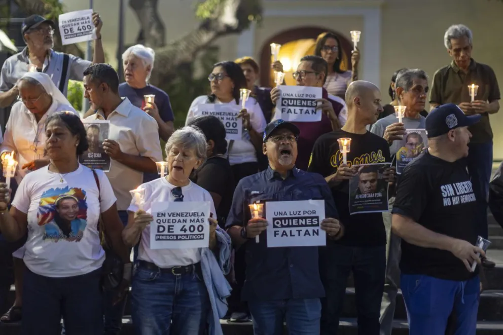 Personas sostienen carteles y velas encendidas en una vigilia para orar por la liberación de los presos políticos en Caracas (Venezuela). EFE/ Miguel Gutiérrez