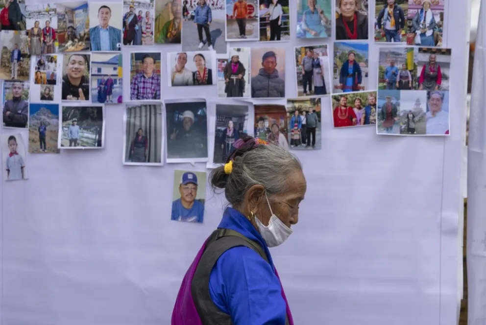 Un familiar pasa por el muro de de fotografías de personas que perdieron la vida en las repentinas inundaciones ocurridas cerca de la frontera entre Nepal y Tíbet. Foto: EFE 
