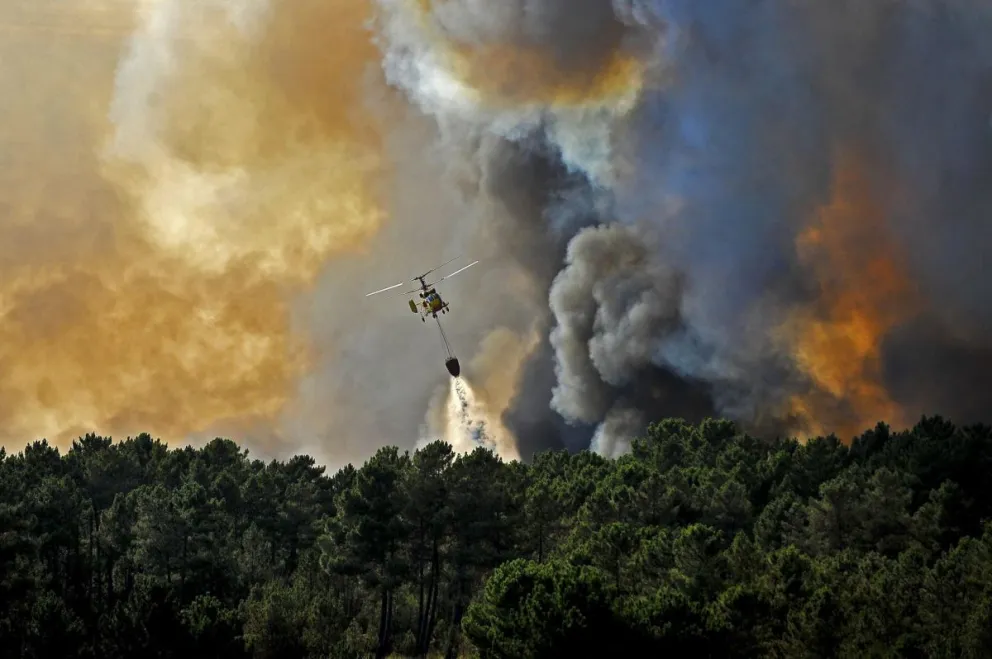 Un helicóptero lanza agua sobre un incendio forestal en Seizures, cerca a Penalva do Castelo (Portugal), en una imagen de archivo. Foto: EFE