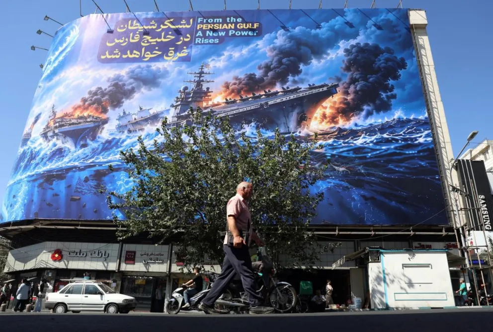 Iraníes caminan junto a una valla publicitaria antiamericana. Foto: EFE 
