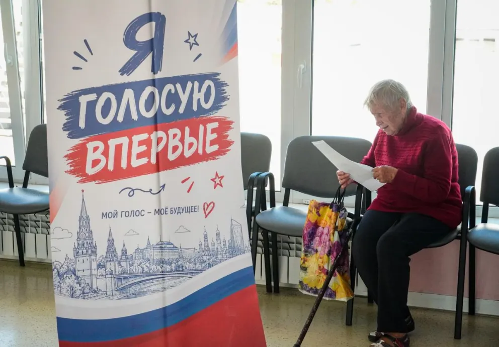 Una mujer examina una papeleta electoral cerca de un cartel que dice 'Voto por primera vez' en un colegio electoral de Mariúpol, en la región de Donetsk, el pasado sábado 19 de septiembre de 2026, durante las elecciones legislativas rusas. Foto: EFE