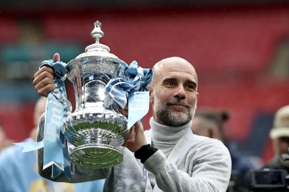 Pep Guardiola, el exentrenador del Manchester City, levanta un trofeo de los varios que ganó con el club. Foto: EFE