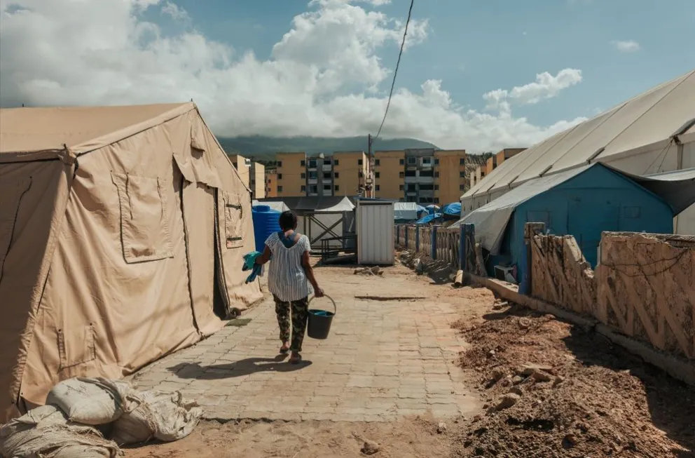 Una mujer lleva un cubo de agua en un campamento provisional instalado a las afueras de Mare Abajo, un complejo de viviendas que se derrumbó parcialmente durante los dos terremotos. Foto: Adriana Loureiro Fernández (MSF)