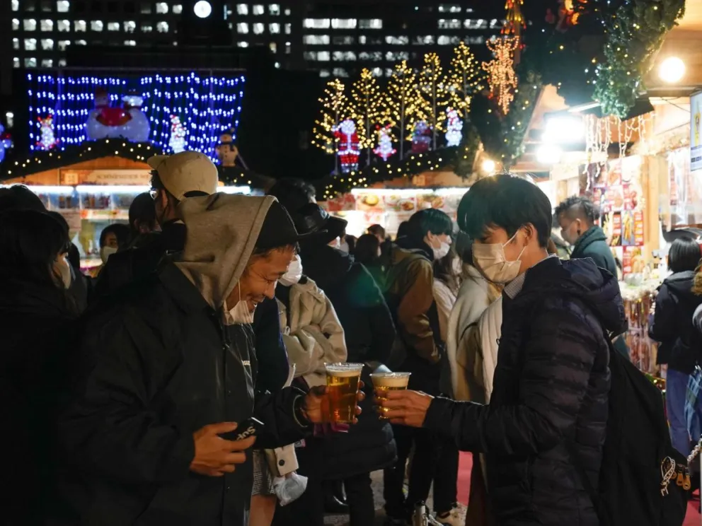 Un grupo de personas tomando cerveza en un mercado navideño. Foto: EFE