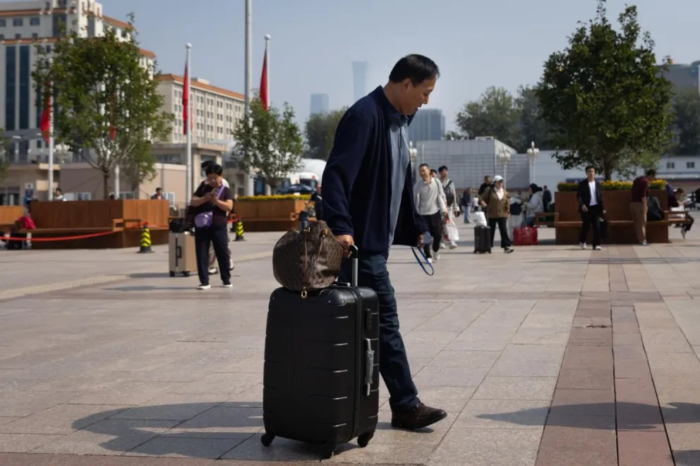 Un hombre carga su maleta en una estación de tren en Pekín, China. Foto: EFE