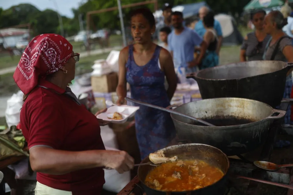 Una mujer sirve alimentos a personas en un parque este sábado, en el centro de Tonosí (Panamá).EFE/ Bienvenido Velasco