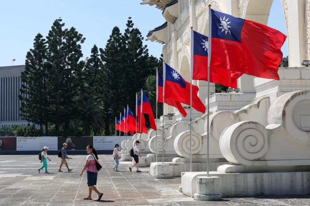 Un grupo de personas caminan por una plaza de Taipei con múltiples banderas de Taiwán. Foto: EFE 
