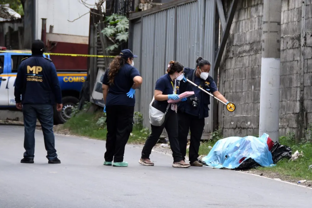 Integrantes del Ministerio Público y de la Policía inspeccionan dos cadáveres hallados en bolsas plásticas y amarrados con lazos a un costado de la carretera antigua a Chinautla (Guatemala). EFE