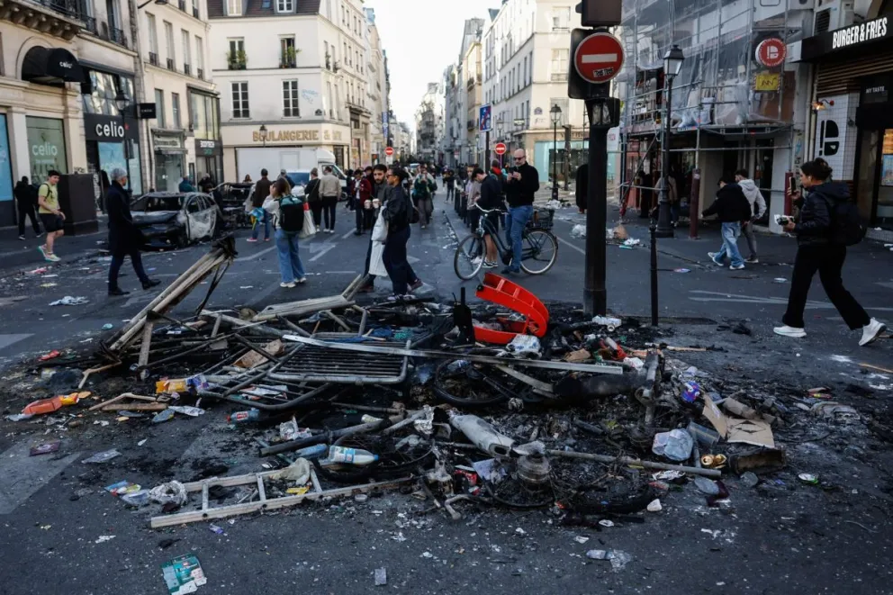 Unas personas observan los escombros que han quedado en la calle tras los enfrentamientos entre la policía antidisturbios y los manifestantes durante las protestas en París, Francia, el 18 de octubre de 2026. Foto: EFE