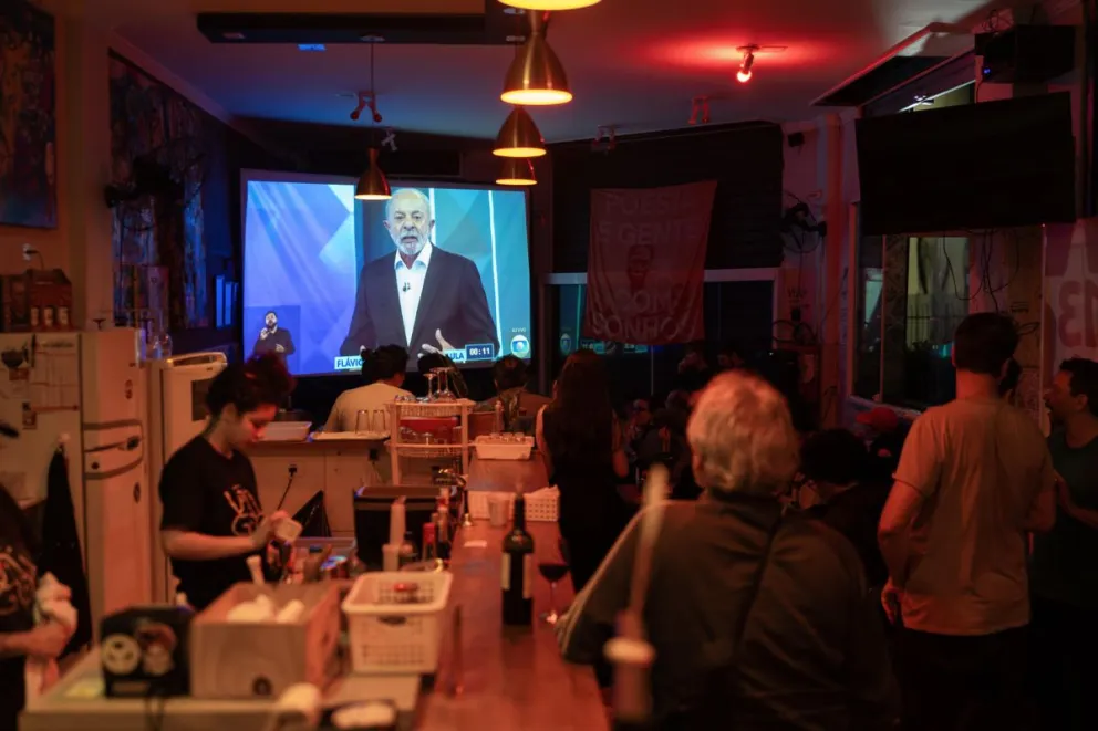 Personas observan una trasmisión del debate entre el presidente de Brasil y candidato a la reelección, Luiz Inácio Lula da Silva, y el candidato de la oposición Flávio Bolsonaro, este viernes en Sao Paulo (Brasil). EFE