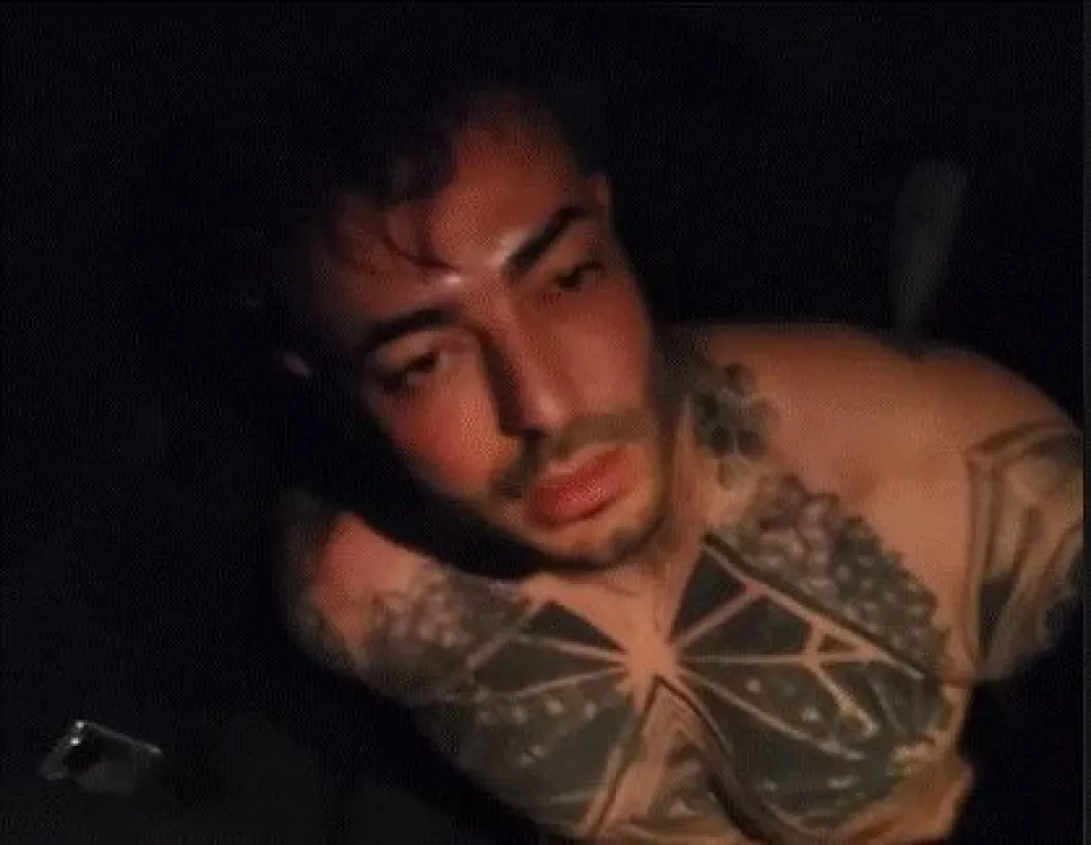 Uno de los videos lo muestra en la parte trasera de un vehículo policial, sin polera y con las manos esposadas detrás de la espalda. Foto: Captura