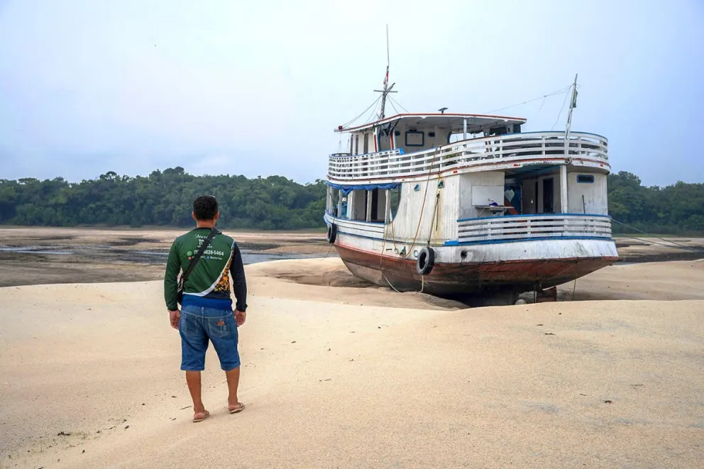 El barquero Roberto Moreira observa el barco 'Comandante Bob', encallado durante el periodo de estiaje de los ríos amazónicos en Anavilhanas. Foto: EFE